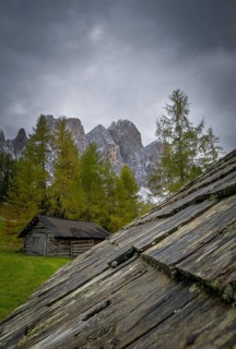 View over a wooden roof of a mountain hut to a part of the Geisler group from the Gampenwiese,
