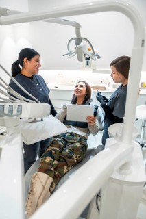 Patient holding a tablet while discussing treatment options with dentists in a modern dental