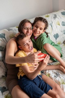 A joyful family shares a tender moment on the couch. The loving mother embraces her daughter with a