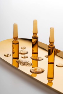 Aesthetic arrangement of cosmetic ampoules filled with anti-aging serum, placed on a reflective