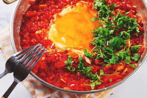 Traditional Turkish dish, scrambled eggs with tomatoes, Menemen, with herbs, in a frying pan,