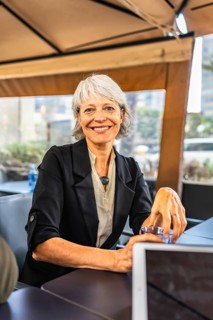 Vertical portrait of a happy caucasian mature business woman drinking coffee in a cafeteria