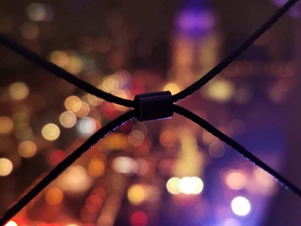 Abstract bokeh view at night with blurred lights and a wire fence in the foreground, lights of the