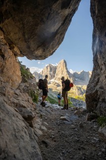 Three mountaineers in a rock cave in front of picturesque mountain landscape in the morning, Cima