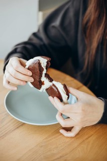 Close-up of a pair of hands pulling apart a whoopie pie, showcasing its creamy filling. The dessert