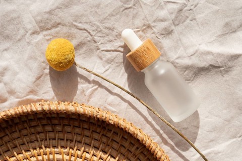 A minimalist scene featuring a cosmetic with a wooden cap on a textured fabric, accompanied by a