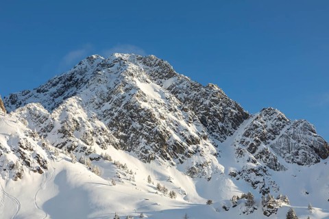 Stunning view of rugged, snow-covered mountain peaks illuminated by bright sunlight against a clear