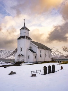 Gimsøy church with cemetery, snow-covered mountains in the background, winter, Gimsøya, Lofoten,