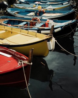 A picturesque scene of vibrant rowboats moored in a quiet Italian port, reflecting the tranquil