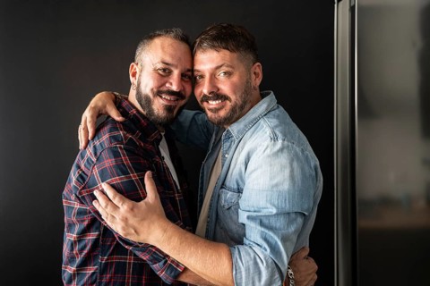 A happy gay couple embraces warmly, showcasing love and connection. Their joyful expressions and