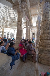 Indian woman praying between the white marble pillars in the Adinath temple in Ranakpur, Jain