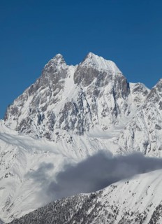 Breathtaking view of a majestic mountain peak covered in snow, set against a clear blue sky in