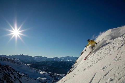 Experience the thrill of freeride skiing on a sunlit, snowy mountain slope A skier in a yellow