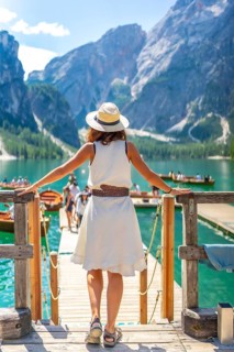 Woman walking on a wooden pier, enjoying the breathtaking view of lake braies and the surrounding