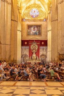 Church interior with gathered people and ornate furnishings, Seville