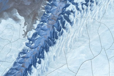 A striking aerial view of a snow-covered mountain range showcasing dramatic peaks and deep valleys.