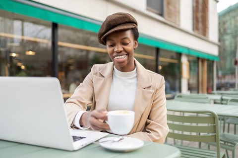 An urban black woman enjoys a coffee at an outdoor cafe while working on her laptop The vibrant