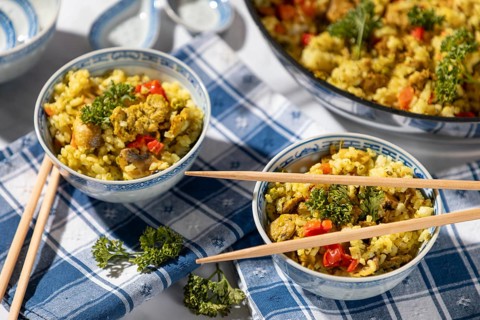 Dishes of fried rice and chopsticks next to the pan, decorated with parsley