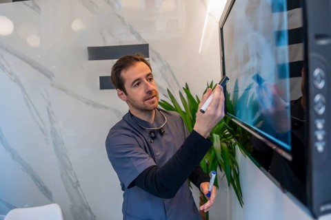 Dentist explaining a dental radiography using a digital screen in a modern and bright clinic