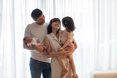 A joyful young family shares a tender moment at home. The image captures a smiling mother and