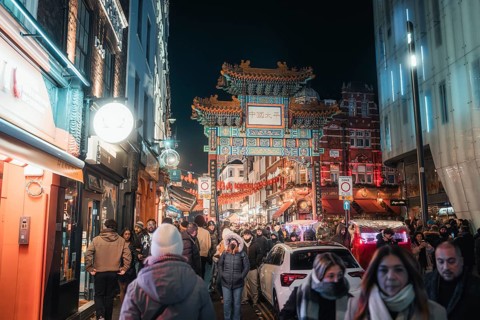 People stroll through Chinatown past an illuminated archway, New Year's Eve London, United Kingdom
