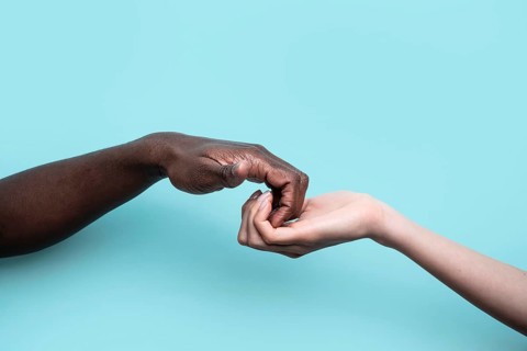 A powerful image depicting two hands of different skin tones gently touching, symbolizing