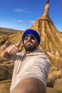 Tourist with blue turban and sunglasses taking a selfie and making thumbs up sign in the bardenas