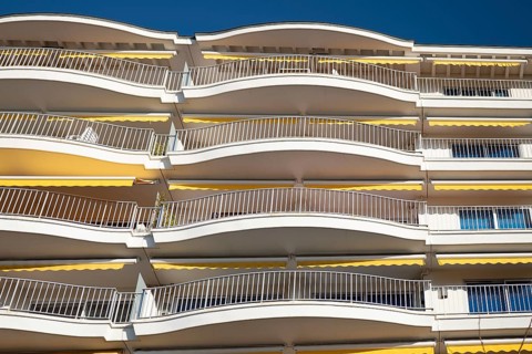 A view of modern apartment balconies featuring a distinct curved design. The light-colored metal