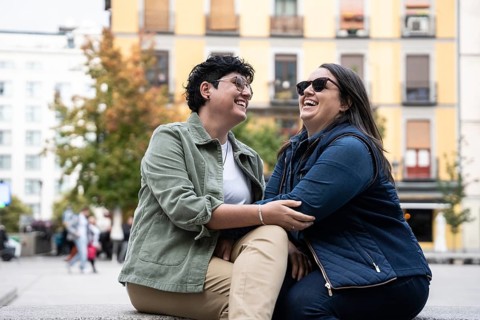 Curvy lesbian couple share a joyful moment outdoors in an urban area. Dressed casually, they enjoy