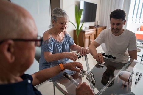 A cheerful multigenerational family gathers in a cozy kitchen to bond over a game of dominoes.