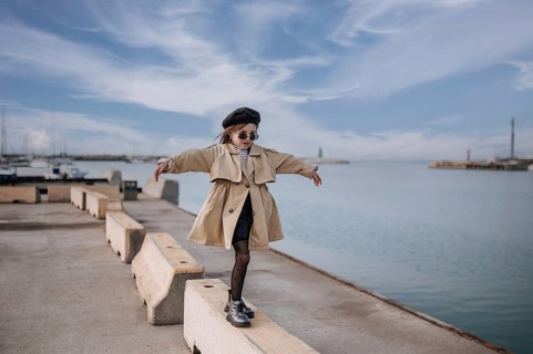 A fashionable girl balances on a concrete barrier at Civitanova's waterfront in Italy. She wears a