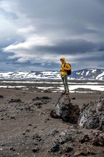 Hikers in snow-covered volcanic landscape with volcanic sand and petrified lava, crater of Askja