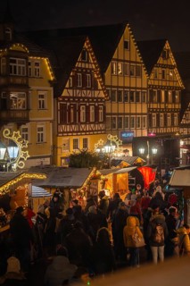 Atmospheric Christmas market with illuminated half-timbered houses and a crowd of people at night,