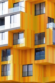 A contemporary building showcases a striking blend of materials with its vibrant orange metal