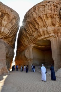 Tourists in front of the divan, Nabataean cult site carved into the rock at Jabal Ithlib, Hegra or