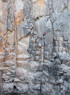 Climbers engage in traditional climbing on a rugged rock face, showcasing endurance and skill. The