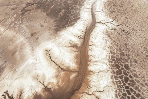 Aerial view of a barren, cracked landscape showcasing intricate patterns of dried earth. The arid