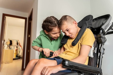A heartwarming image of two disabled friends, a boy with cerebral palsy and a girl with a