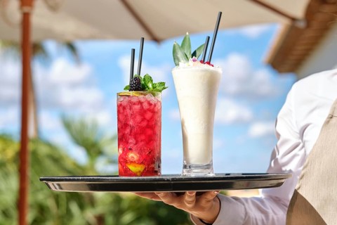 Two vibrant cocktails on a tray, featuring a red berry drink and a creamy pina colada. Captured
