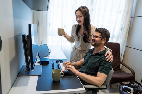 A diverse couple enjoys a cozy day at home, sharing a moment as they engage with their computer.