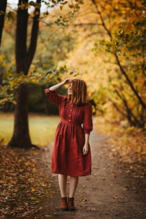 A woman in a red dress enjoys a peaceful walk through a vibrant autumn forest in Quebec, Canada.