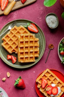 Delicious homemade waffles topped with strawberries and yoghurt on a rustic plate. A cozy and