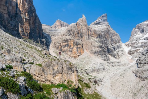 Hiker looking into a mountain valley, Castelletto Superior and Cima Sella mountain peaks, Bocca di
