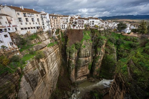 Scenic view looking down into the lush green El Tajo gorge in Ronda, showing the river and the
