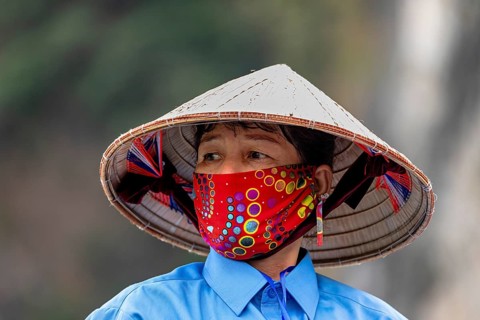Woman with traditional hat and colourful face mask in natural environment, Vietnamese with straw