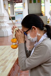 Bangkok, Thailand. February 20th 2025. A Thai visitor prays and makes an offering at The Wat Suthat