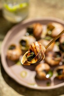 Close-up image of baked escargot garnished with parsley and butter, served in a circular dish with