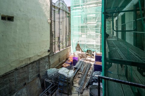 A construction site with scaffolding and building materials like metal rods, bricks, and nets. The