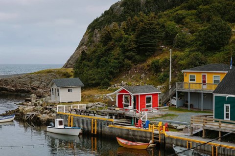 Quaint and colorful fishing huts line the shores of St. John's, Newfoundland. Nestled against lush