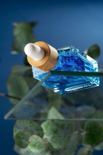 A cooling face care serum for men, showcased in a stylish dropper bottle with vibrant blue liquid,